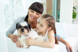 women and little girl holding small dog